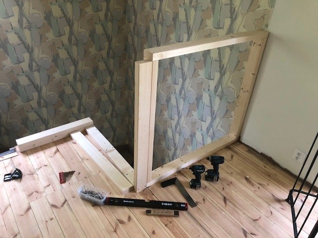 Renovering av hall med halvfärdigt trä- och gipsräcke under konstruktion, verktyg och byggmaterial på golvet.