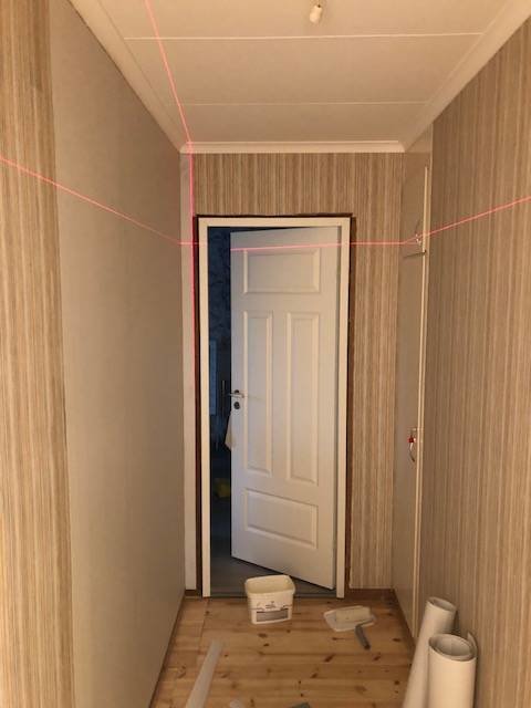 Renoveringstapet uppsatt i en hall med synliga skarvar och målarutrustning på golvet.