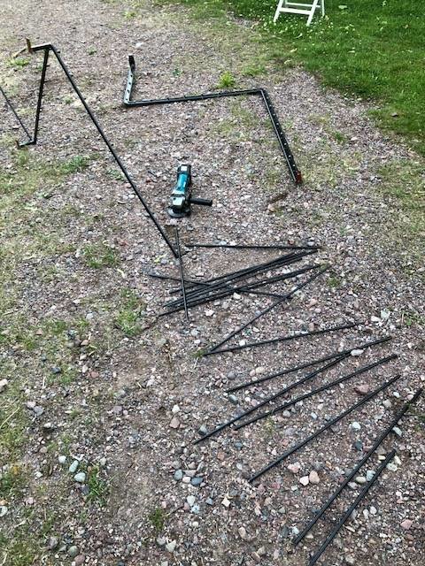 Demonterat svart metallräcke bredvid elverktyg på grusmark, indikerar återbruk i ett byggprojekt. #återbruk