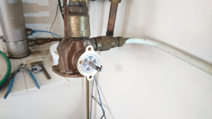 Ventil med avlägsnat huvud visande ett vitt plasthjul och mekaniska kopplingar mot en rörinstallation.