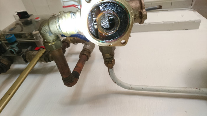 Närbild på öppnad automatisk ventil med synlig mekanisk styrning och kopplingar, i en byggmiljö.