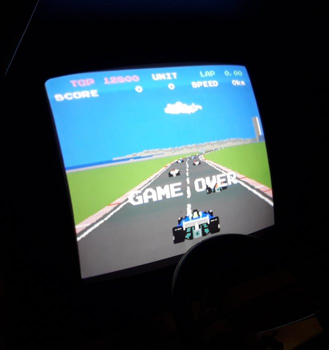 CRT-skärm som visar en pixelerad racingvideospelsskärm med texten "GAME OVER". Stökigt i förgrunden.