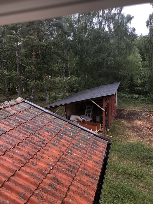 Upprättad vedbod med provisoriska stag och strävor synlig bakom ett tegeltak.