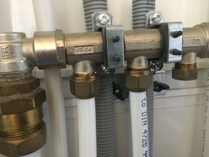 Vattenrör och LK-fördelare med mässingskopplingar och mätare för badrumsrenovering.