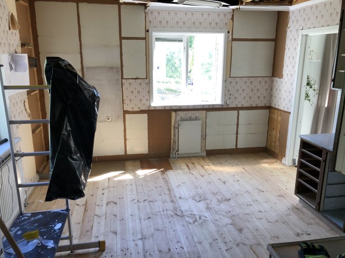 Kök under renovering med tomma väggar, avlägsnat kakel och golv synligt.