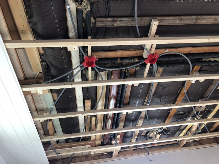 Renoverat elsystem med nya kablar och röda eluttag monterade på reglar under ett öppet tak i ett hus.