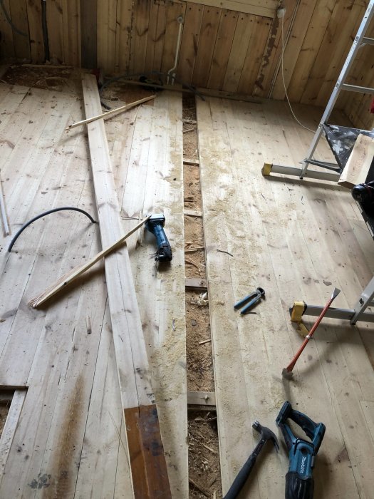 Ett pågående renoveringsrum med verktyg och öppnat golv för avloppsinstallation.