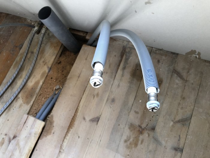 Alu-PEX rörledningar framdragna genom ett golv, redo för anslutning vid badrumsrenovering.