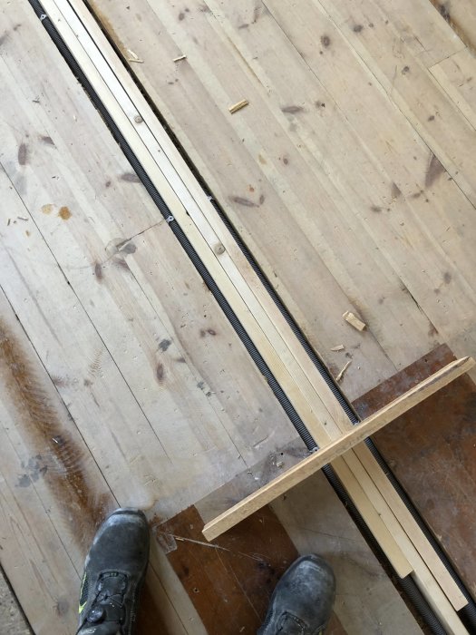Uppskurna trägolv visar nya avloppsrör och förberedda rörinstallationer för en badrumsrenovering.