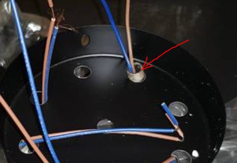 Närbild på elinstallation med blåa och bruna ledningar, samt en röd pil som pekar mot en trolig felaktig kabelanslutning.