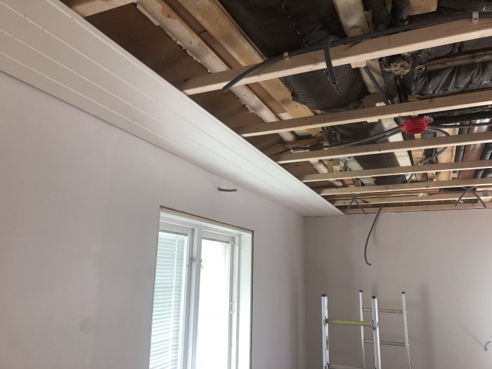 Installation av vita takbrädor i ett pågående byggprojekt med öppen takkonstruktion och markerade platser för spottar.