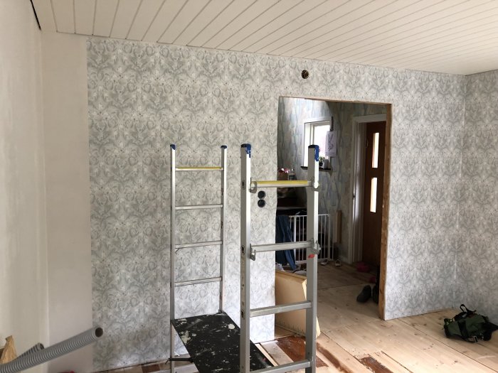 Ny tapet med blommigt mönster i rum under renovering med stege och oskarp bakgrund.
