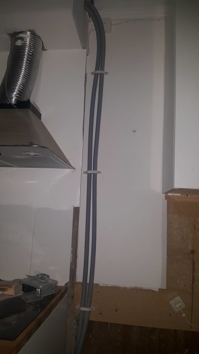 Plaströr installerade längs en vägg ovanför köksbänk och anslutna till befintlig ventilation.