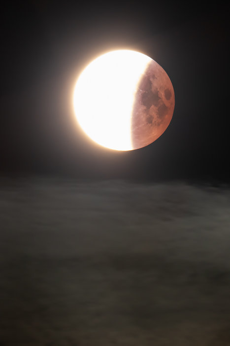 Delvis upplyst måne under en förmörkelse mot en mörk himmel.