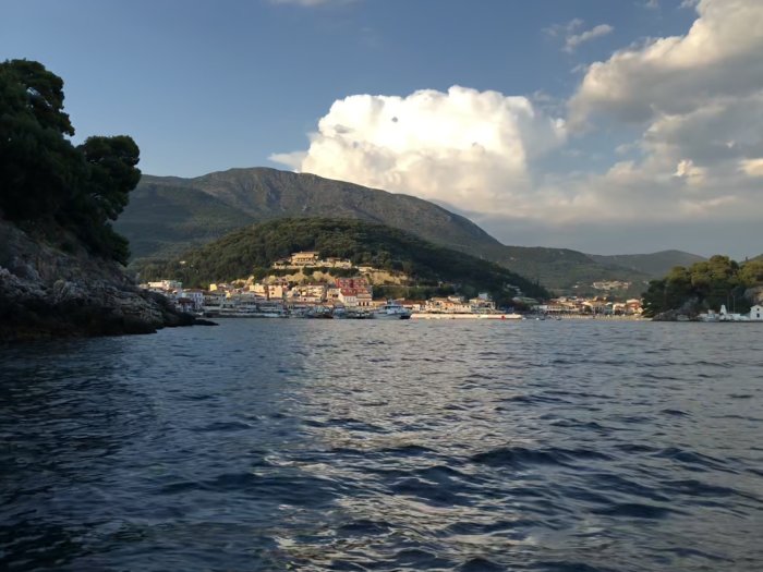 Utsikt från båt mot kuststaden Parga med hus, båtar och berg i bakgrunden.