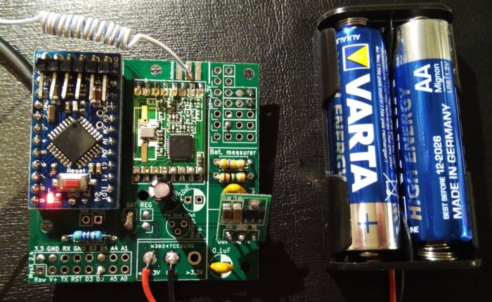 EasyPCB Revision 10 med en NRF24L01+ amplifier, extern volt-regulator, och batterimätare bredvid två AA-batterier.