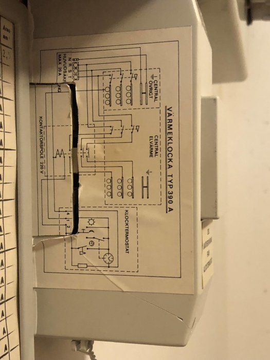 En termostat med ett öppet lock visar en elektrisk schemaetikett med texten "VÄRMEKLOCKA VP390A" och kretsscheman.