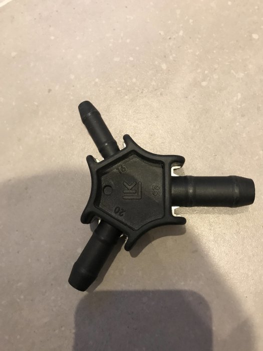 Svart plastverktyg för kalibrering och gradning av rör som ligger på ett grått underlag.