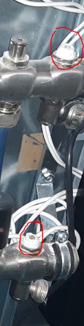 Närbild på golvvärmesystems fördelare med markerade urtappningsventiler och anslutning för trädgårdsslang.