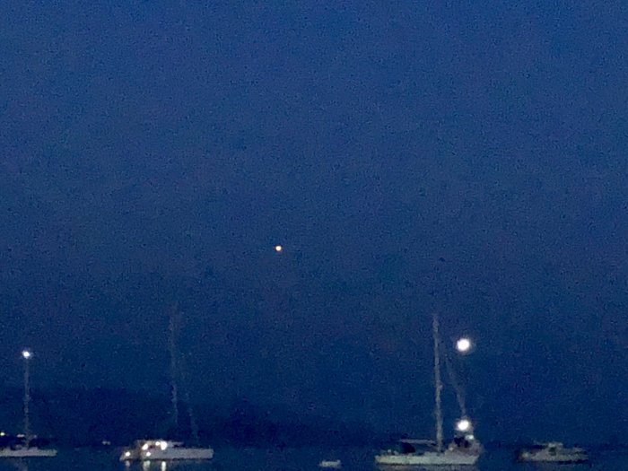 Kvällsbild över havet med orange punkt som representerar Mars och silhuetter av båtar.