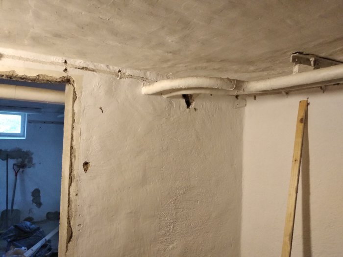 Vita rör längs en betongvägg och tak med synlig skarv och hålighet där nya rör kan dras för att omdirigera vattenledningar.