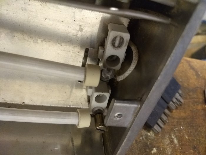 Närbild på trasig maskindel med fokus på en vit plastkomponent och kugghjul inne i maskineri.