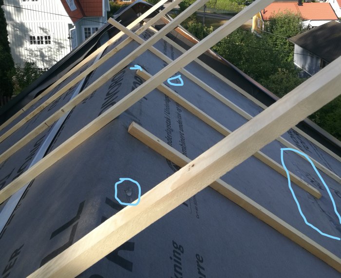 Takstolar med synliga veck och tårar i underlagspappen på ett hus under konstruktion.