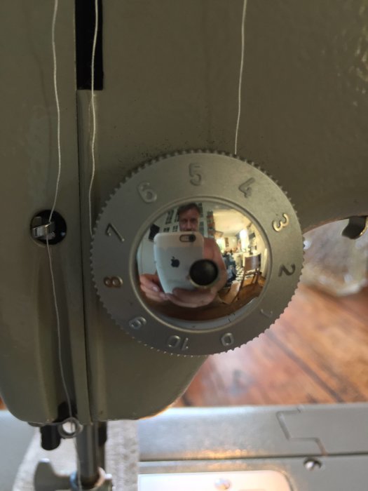 Reflektion av person som fotograferar en PFAFF 360 Automatic symaskin, med detalj av inställningshjul.