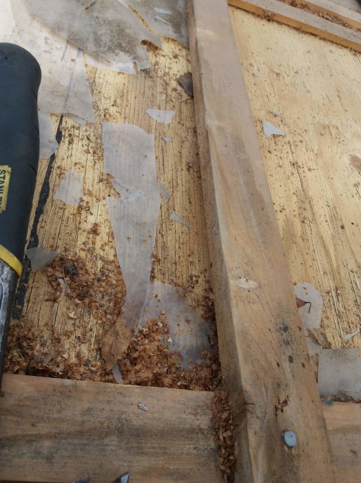 Närbild av plywood med plastrester, många skarvar och en masonitskiva vid skarvarna.