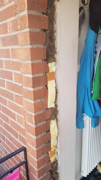 Träkilar installerade mellan tegelvägg och isolering för att stärka konstruktionen.