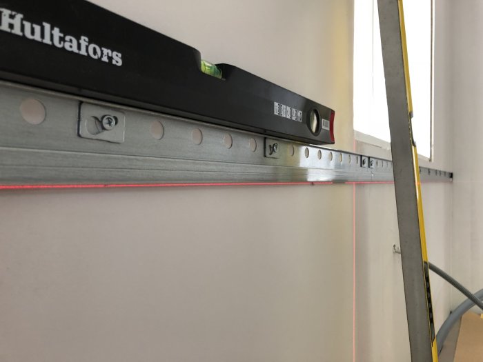Vattenpass från Hultafors och laserlinje vid montering av köksskåp.