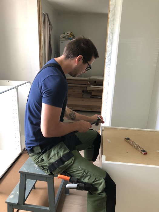 Man monterar IKEA-möbler i arbetskläder med verktyg i handen.