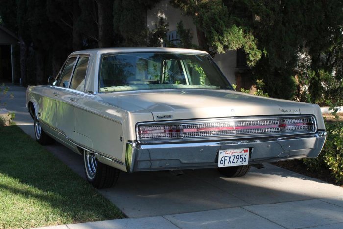 En beige 1968 Chrysler New Yorker parkerad med bakre delen synlig framför ett bostadshus.