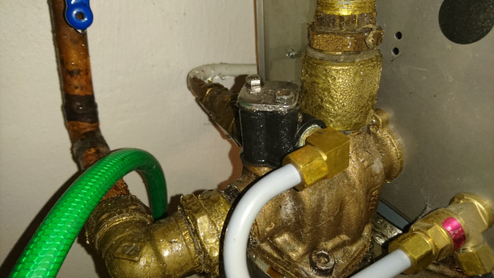 Närbild på vattenreningsutrustning med igensatt vitt utloppsrör och svart injektormunstycke.