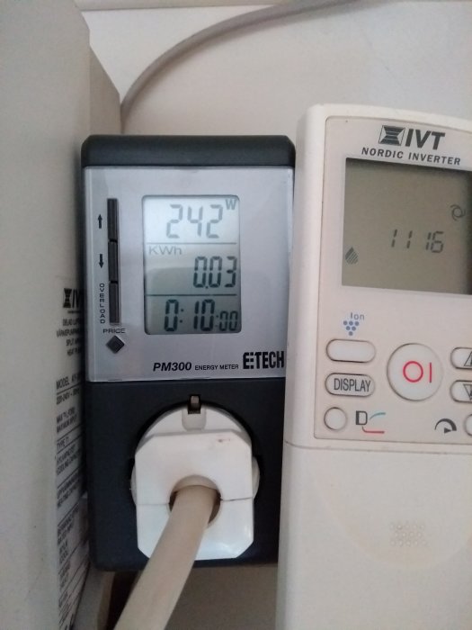 Energimätare som visar 242 watt och avfuktarens panel i ett hus, för att demonstrera strömförbrukningen.