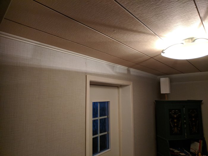 Inredning med halvfärdig vägg-takanslutning under renovering, isolering syns ej, taklampa och fönster.