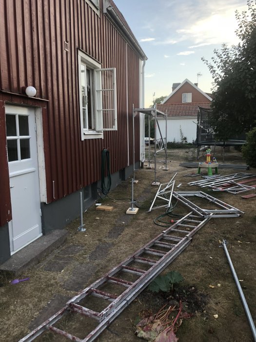 Nyrenoverad husfasad med avvattning och hängränna, ställningsdelar nedmonterade på marken.