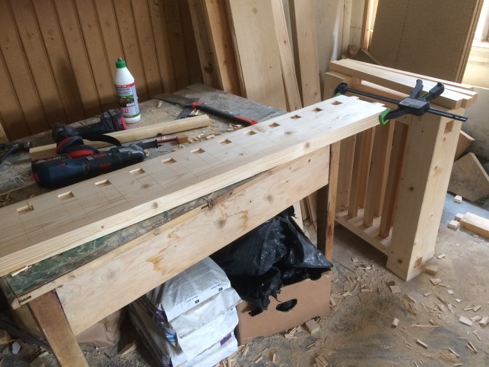 Processen av att bygga ett träbalkongräcke i arbetsrummet med verktyg och träbitar runtomkring.
