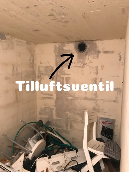 Kallförråd med tilluftsventil och röriga förvarade föremål på golvet.