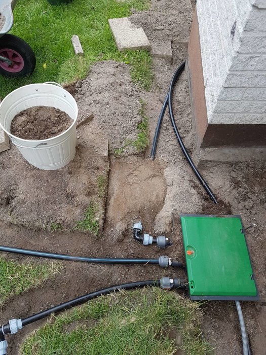 Installation av bevattningssystem med Gardena sprinklerventiler och slangar längs en nyskött gräsmatta och jordkant.