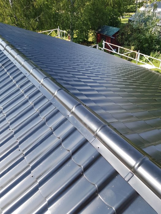 Nyinstallerat plåttak med takfotsränna i en lummig trädgårdsmiljö.