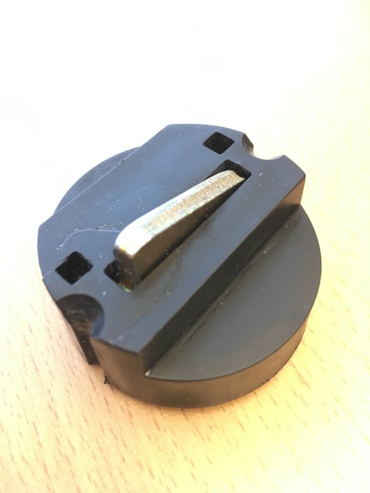 Svart fönsterspärr "puck" för vädringsläge på en ljus bakgrund.