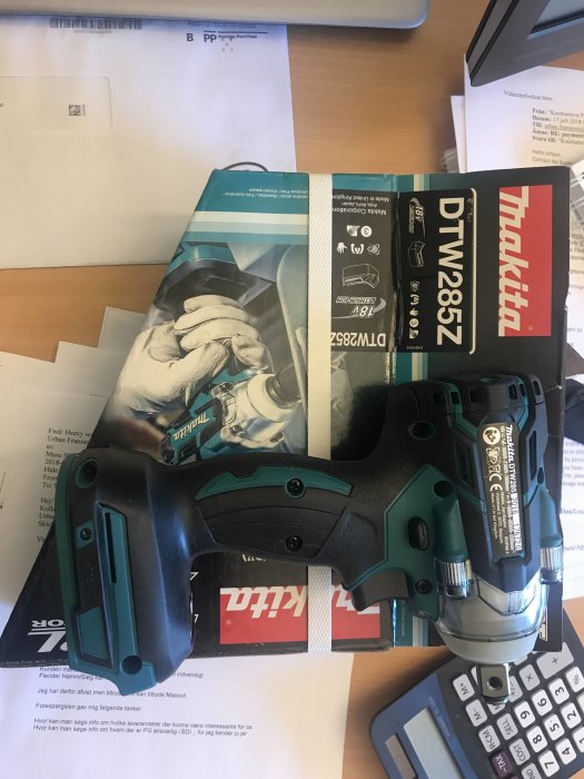 Makita DTW285Z slagskruvdragare på ett skrivbord med förpackning och pappersarbete.