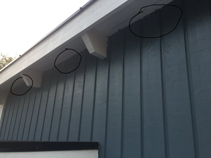 Gråmålat väggparti på friggebod med tre markerade platser för borrning av ventilationshål.