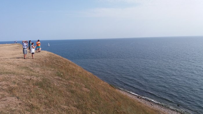 Personer på en kustklippa vid havet, Sandhammaren och Kåseberga, klar himmel.