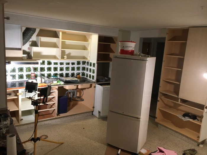 Kök under renovering med slipade skåpluckor, ny målarfärg och köksutrustning borttagen.