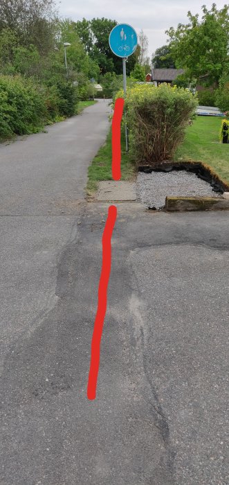 Asfalterad gångväg med röda markeringar som illustrerar fiberkabelns väg, skylt med gående och cyklist i bakgrunden.