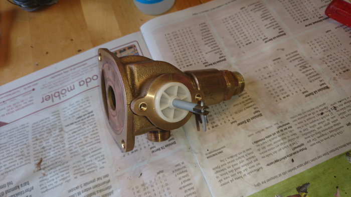 Renoverat vattenfilter med nya distanser och kolv, ligger på en tidning, inga specialverktyg synliga.