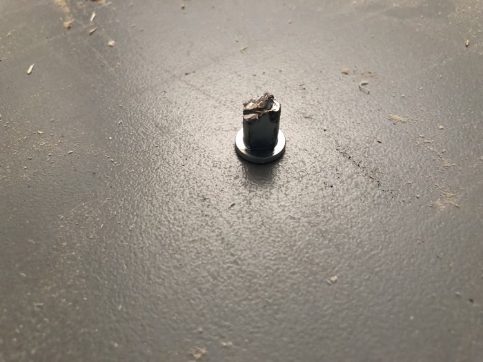 Brottsstycke av klingskydd på verkstadsgolv efter avlossning under kapning.