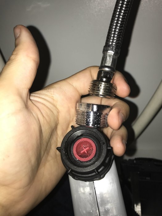 Hand håller en vattenanslutning till diskmaskin med synlig packning som möjligen behöver tätning.